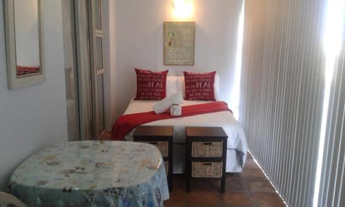 - une chambre avec un lit doté d'oreillers rouges et d'une table dans l'établissement LANGEBAAN, à Langebaan