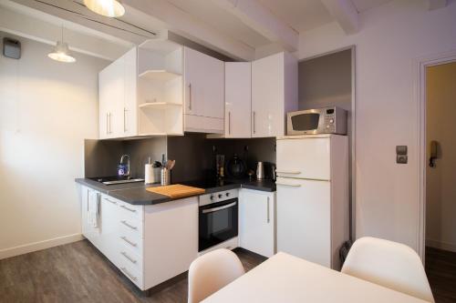 uma cozinha com armários brancos e um frigorífico branco em Le rohan sawadee em Colmar
