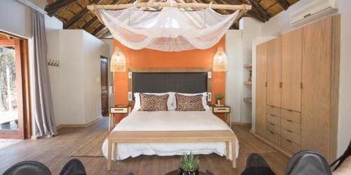 een slaapkamer met een groot bed en een oranje plafond bij Ntamba Safari Lodge in Matlhagame