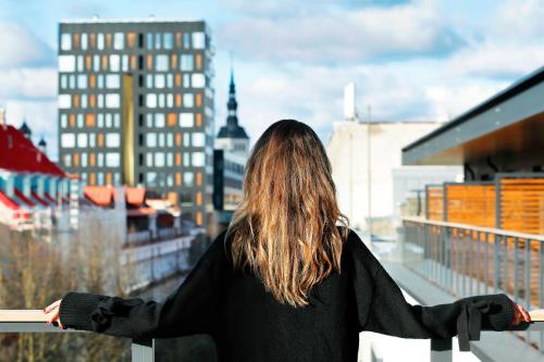 a woman standing on a balcony overlooking a city at Hestia Hotel Kentmanni in Tallinn