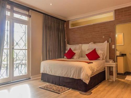 1 dormitorio con 1 cama grande con almohadas rojas en 59 on Central en Johannesburgo