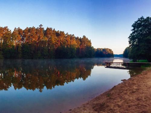a view of a lake with trees reflecting in the water at Przystanek Tleń in Tleń