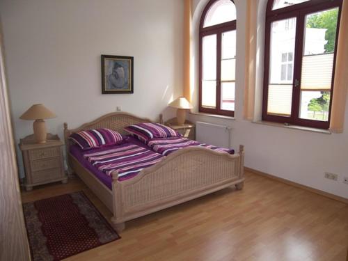 um quarto com uma cama com lençóis roxos e 2 janelas em Haus Lucie em Heringsdorf