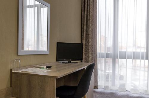 a desk with a computer in a room with a window at Семеен Хотел Естило in Dimitrovgrad