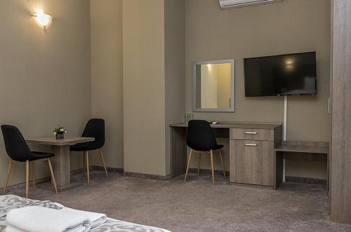 a hotel room with a tv and a table and chairs at Семеен Хотел Естило in Dimitrovgrad