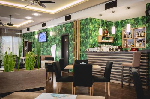 a restaurant with a green wall with tables and chairs at Семеен Хотел Естило in Dimitrovgrad