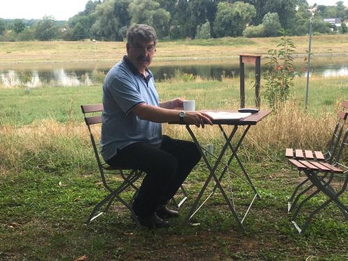 a man sitting at a table with a coffee cup at Pension Elbkiosk in Kleinzadel
