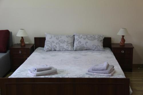 a bed with two pillows on it with two night stands at Apartments Domovik ,Kirilla i Mefodiya, 5 in Mukacheve