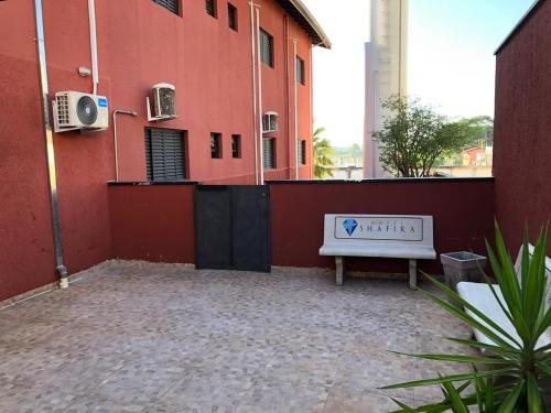 a bench in front of a building with a sign on it at Shafira Hotel in Limeira