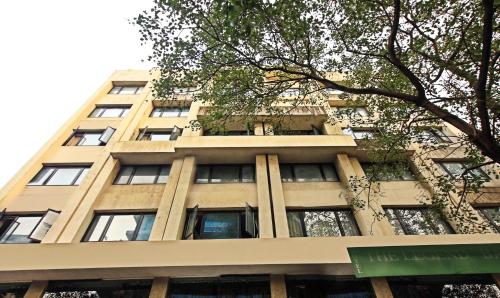 um edifício alto e bronzeado com janelas e uma árvore em The Legend Hotel- Santacruz Near Mumbai International Airport em Mumbai