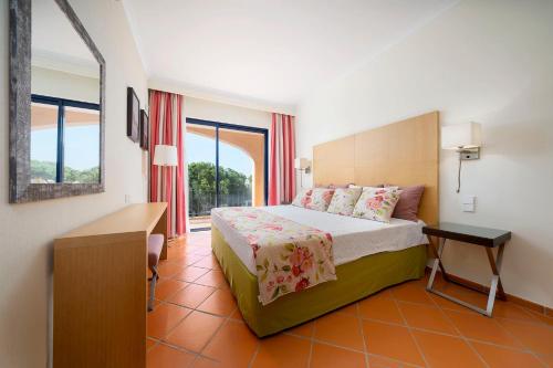 a bedroom with a bed and a desk and windows at AL - Apartamento Vila Sol F5 Top Floor in Quarteira