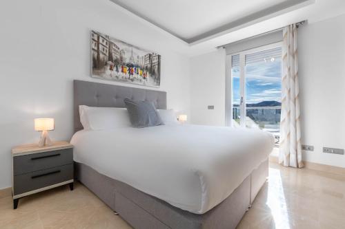 a white bedroom with a large bed and a window at Apartment front Line La Cala Golf Resort in La Cala de Mijas