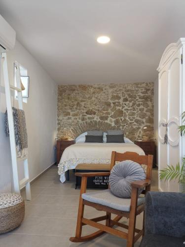 a bedroom with a bed and a stone wall at TRIPERIA 25 in Medina Sidonia