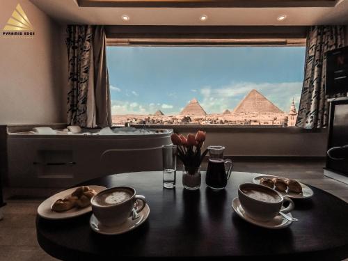 uma mesa com duas chávenas de café e vista para as pirâmides em Pyramid Edge Hotel no Cairo