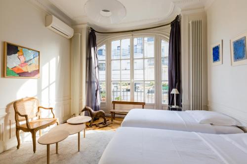 a bedroom with two beds and a chair and a window at Veeve - Haussmann Beauty in the 6th in Paris