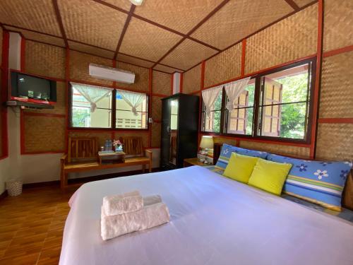 1 dormitorio con 1 cama grande con almohadas amarillas y azules en Yayee Homestay, en Sai Yok