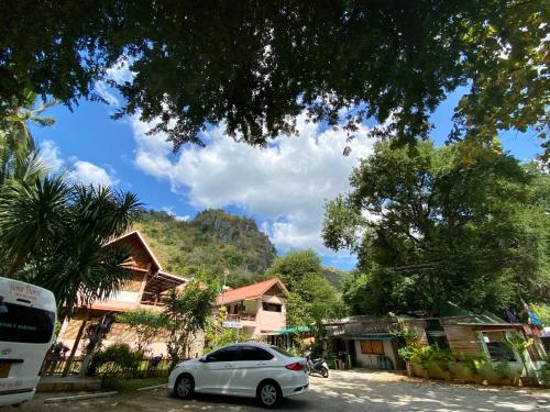 a white car parked in a parking lot next to houses at Yayee Homestay in Sai Yok