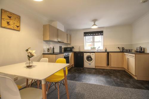 a kitchen with a table and yellow chairs in it at 4 Dbl Beds, Modern Apartment, Free Parking and Home-from-home in Wakefield