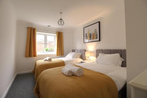 een slaapkamer met 2 bedden en handdoeken bij Central, Stylish 2-bed Apartment, with allocated parking in Wakefield