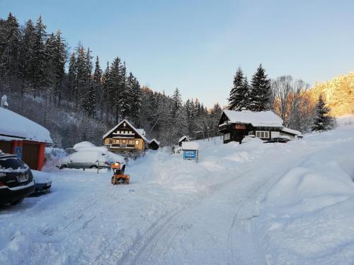 a snow covered yard with a house and a road at Pension Vladimír in Janske Lazne