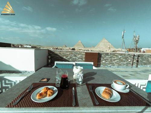 uma mesa com dois pratos de comida no topo de uma pirâmide em Pyramid Edge Hotel no Cairo