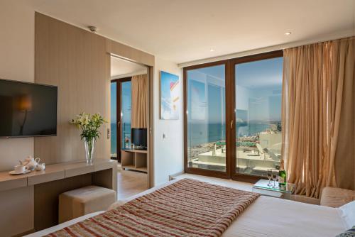 a bedroom with a large bed with a large window at Kriti Beach Hotel in Rethymno Town