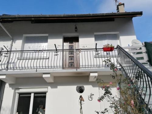 uma casa branca com uma varanda com uma porta em Appartement au coeur de la maurienne em Saint-Étienne-de-Cuines