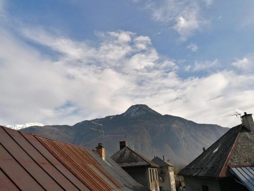 uma montanha à distância atrás de telhados de casas em Appartement au coeur de la maurienne em Saint-Étienne-de-Cuines