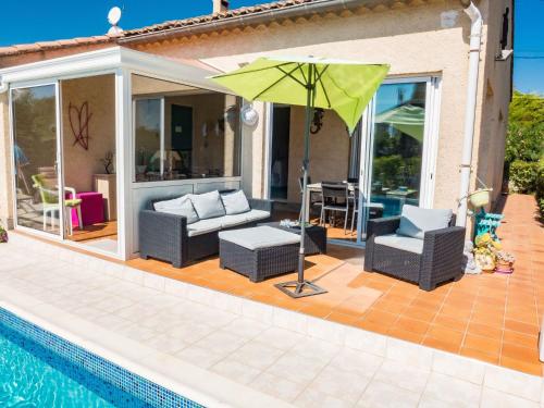 アルジュリエにあるHoliday Home in Argeliers with Swimming Poolのプールサイドのパティオ(ソファ、パラソル付)