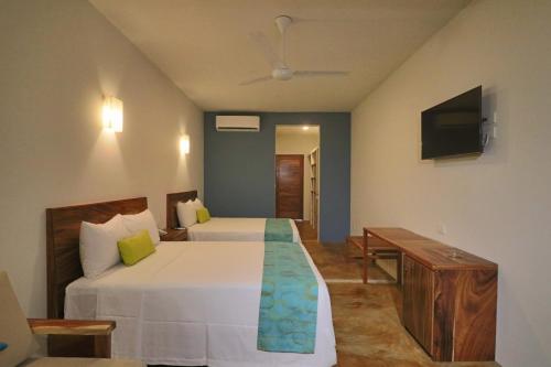 a hotel room with two beds and a television at Punta Zicatela Hotel - Adults Only in Puerto Escondido