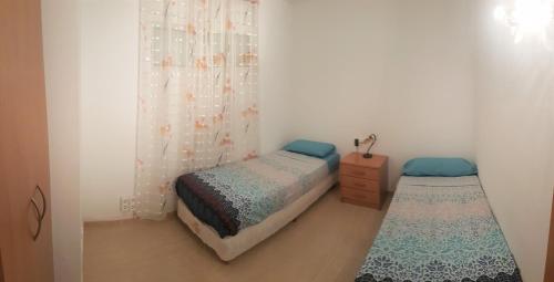 um pequeno quarto com 2 camas individuais e uma cómoda em Magnífico apartamento junto al canal principal. em Empuriabrava