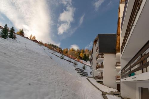 a snow covered hill next to a building at Apartment Mont-Parrain in La Tzoumaz
