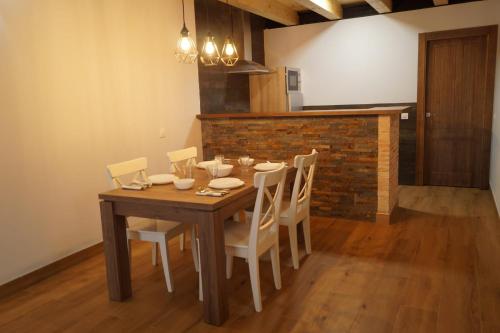 mesa de comedor con sillas blancas y pared de ladrillo en Puente viejo de Buitrago casa Fresno, en Buitrago del Lozoya