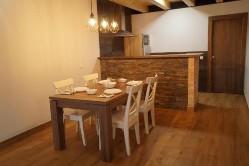 a dining room table with white chairs and a brick wall at Puente viejo de Buitrago casa Fresno in Buitrago del Lozoya