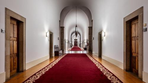 an aisle with a red carpet in a hallway at Pousada Mosteiro de Guimaraes in Guimarães