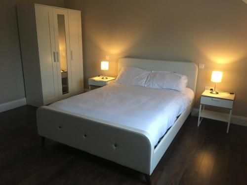 1 dormitorio con 1 cama blanca grande y 2 lámparas en Wainsfort House en Blacklion