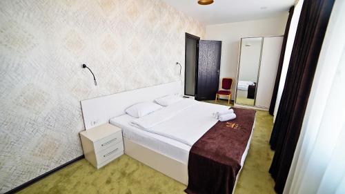 a bedroom with a large white bed and a mirror at Plaza Inn Batumi in Batumi