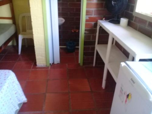 a kitchen with a red tile floor and a white table at restaurante pousada gaucha bigode in Passo de Torres