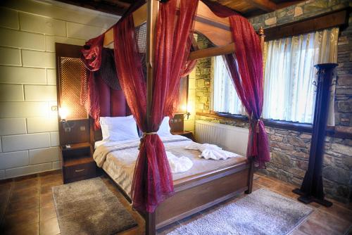 1 dormitorio con cama con dosel y cortinas rojas en Hotel Παραδοσιακο, en Kato Loutraki