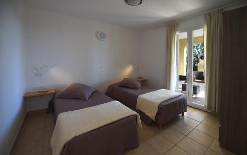 a hotel room with two beds and a balcony at Résidence Chiar' Di Luna in Sainte-Lucie de Porto-Vecchio