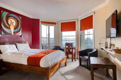 ブライトン＆ホーブにあるAmsterdam Hotel Brighton Seafrontのベッド、テーブル、椅子が備わるホテルルームです。
