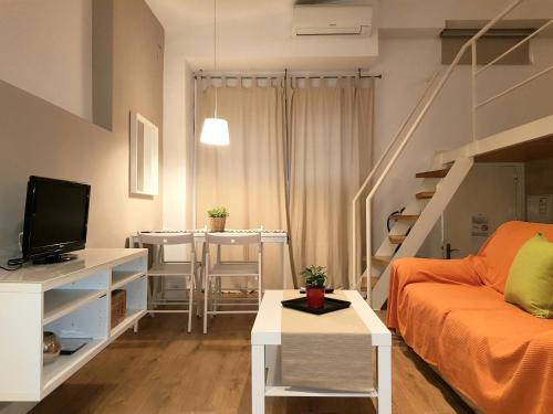 sala de estar con sofá naranja y escalera en Apartamentos Clavero, en Málaga