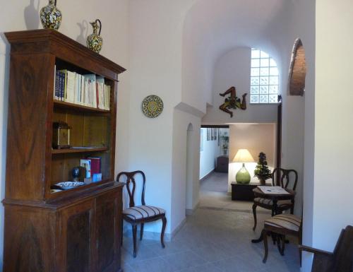 uma sala de estar com uma estante de livros e cadeiras em La Durlindana B&B em Acireale