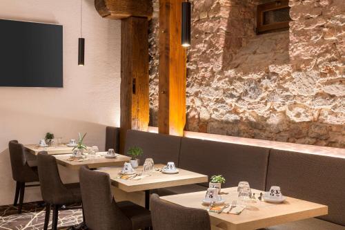 a dining room with tables and chairs and a stone wall at Hotel KLE, BW Signature Collection in Kaysersberg