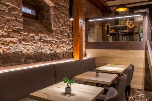 two tables and chairs in a restaurant with a stone wall at Hotel KLE, BW Signature Collection in Kaysersberg