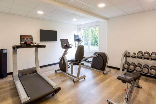 a gym with three exercise bikes and a flat screen tv at Best Western L'Aquarium Arras Nord in Fresnes-lès-Montauban