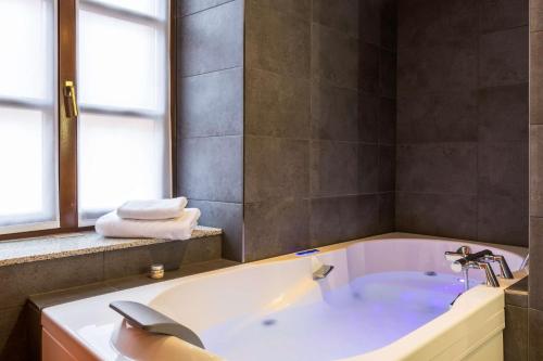 a bathroom with a bath tub with a window at Hotel KLE, BW Signature Collection in Kaysersberg