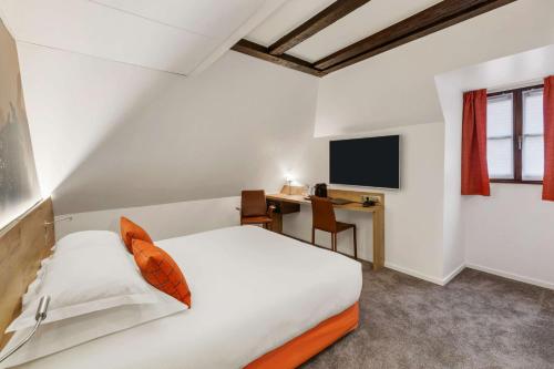 a bedroom with a bed and a desk with a television at Hotel KLE, BW Signature Collection in Kaysersberg