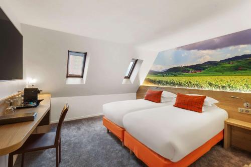 a hotel room with a bed, chair, table and a painting on the at Hotel KLE, BW Signature Collection in Kaysersberg