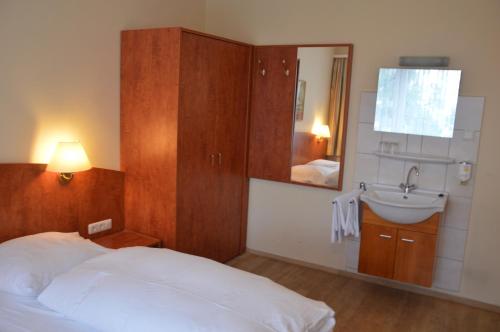 Schlafzimmer mit einem Bett, einem Waschbecken und einem Spiegel in der Unterkunft Hotel Wikinger Hof in Hamburg